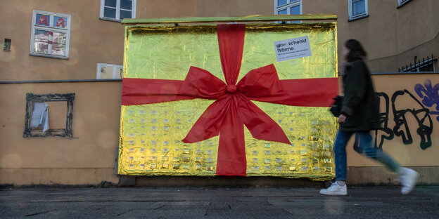 Mit Goldfolie und roter Schleife verzierte Werbetafel als Obdachlosenhilfe in Berlin