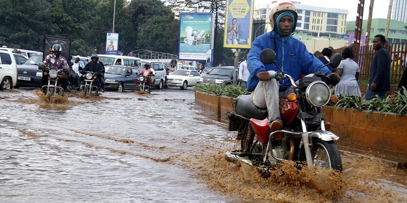 Ein Motorradfeahrer fährt eine Straße entlang, die unter Wasser steht