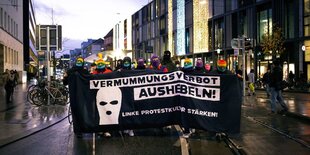 Hinter einem Banner mit der Aufschrift "Vermummungsverbot aushebeln, linke Protestkultur stärken" stehen vermummte Menschen