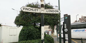An einer Straßenecke stehen Schilder, eines weist "London" aus, eines "Finchley"