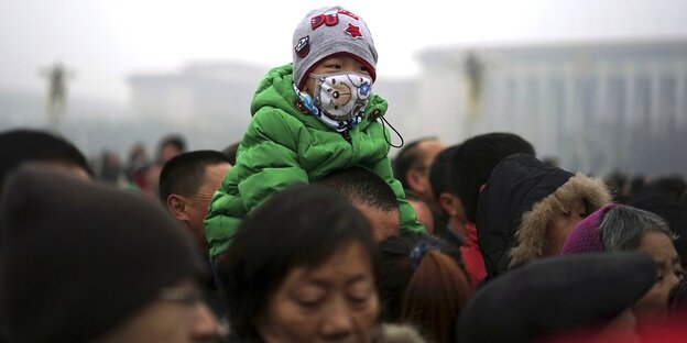 Ein Kind trägt eine Schutzmaske und sitzt auf den Schultern eines Erwachsenen