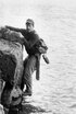 Der Autor Hugo Pratt hängt an einem Felsen über dem Meer