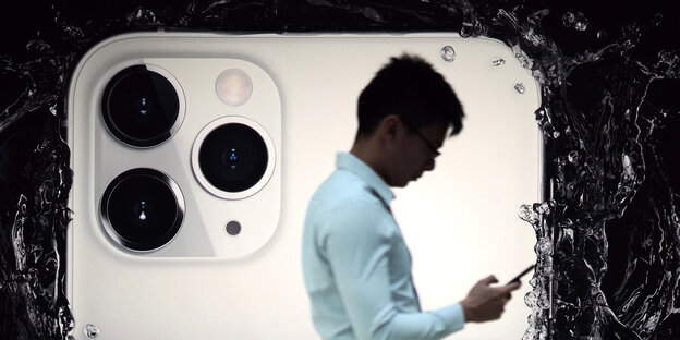 Ein Mann mit Smartphone vor einer riesigen Apple-Werbewand