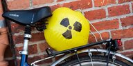 Auf dem Gepäckträger eines Fahrrads ist ein gelber Luftballon mit dem Zeichen für Radioaktivität festgeklemmt