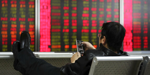 Aktienkurse in einem Snartphone vor einer Wand mit Uahlen