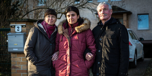 Das Ehepaar Beatrix und Bernd Metzner steht vor seinem Haus in Teltow, in ihrer Mitte steht die Syrerin Heba Abazeid.