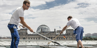 Menschen putzen Solarzellen auf dem Dach des Kanzleramts