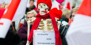 Ein Gerippe trägt ein Schild um den Hals, auf dem steht: "Ich brauche keine Betriebsrente mehr."