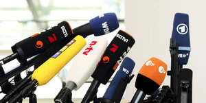 Mikrofone verschiedener Fernsehsender bei einer Pressekonferenz.