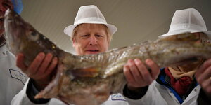 Boris Johnson hält einen Fisch in den Händen