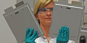 Frau hält zwei DinA4-gro0e Lithium-Ionen-Zellen in der Hand