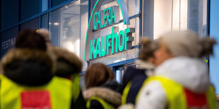 Demonstranten stehen während eines Streiks von Kaufhof- und Karstadt-Beschäftigte vor einem Galeria Kaufhof.