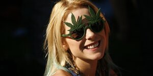Junge Frau mit einer Sonnebrille in Hanfblätterform