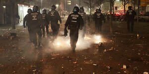 Silvesternacht in Berlin-Schöneberg: Behelmte Polizisten gehen auf Streife inmitten von Raketen und Böllern