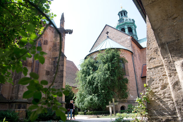 Grüner Busch, der bis zur Dachkante der Apsis, darüber wird ein Teil eines grünen kupferverkleideten Türmchens sichtbar Grüner Busch, der bis zur Dachkante der Apsis, darüber wird ein Teil eines grünen kupferverkleideten Türmchens sichtbar