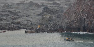 Ein Rettungsboot nähert sich der grauen Vulkaninsel.