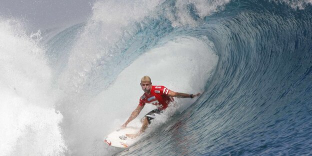 Ein Surfer gleitet auf seinem Brett durch eine sich brechende Welle