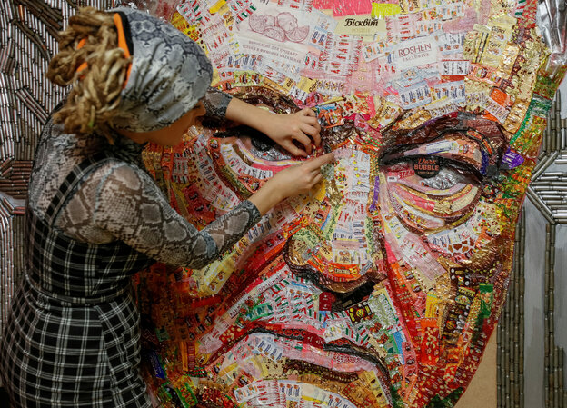 Frau arbeitet an einer bunten Collage, die ein überdimensionales Gesicht zeigt