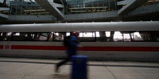 Mensch rennt über Bahnsteig. Ein ICE hält im Hintergrund.