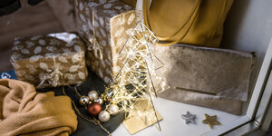 Ein Draht-Weihnachtsbäumchen mit Mini-LED-Lichterkette und goldenen Päckchen