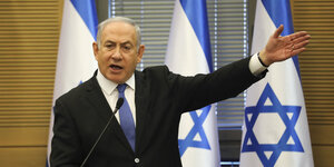 Israels Regierungschef redet vor mehreren israelischen Fahnen
