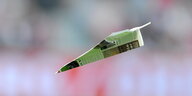 Ein grüner Papierflieger fliegt durch die Luft.