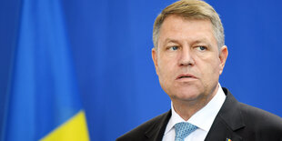 Klaus Iohannis vor einem blauem Hintergrund.