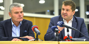 Zwei Politiker hinter einem Tisch mit Mikrophonen