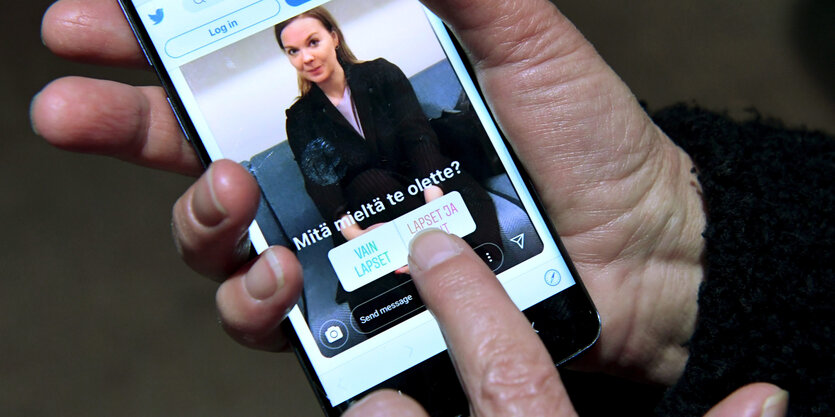 Eine Hand hält ein Smartphone, auf dem eine Frau zu sehen ist.