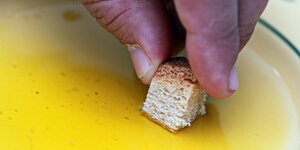 Stück Brot wird in Olivenöl getunkt