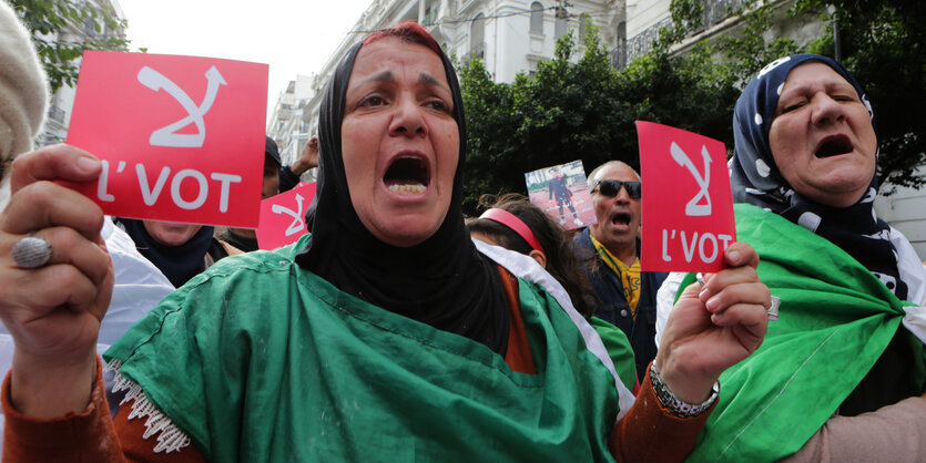 Zwei Frauen halten auf einer Demonstration Schilder in die Höhe.