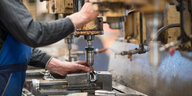 Ein Mitarbeiter bedient in der Produktionshalle der Firma Impulsa AG eine Maschine zur Verarbeitung von Metall.