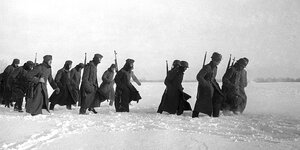 Wehrmachtssoldaten marschieren durch eine Schneelandschaft