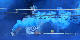 Ein maskierter HSV-Fan zündet Pyrotechnik im Stadion.