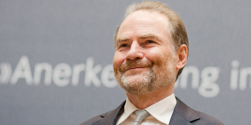 Der Historiker Timothy Garton Ash steht lächelnd vor einer grauen Wand