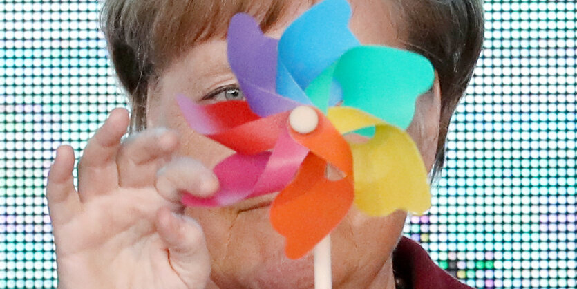 Angela Merkel (CDU), Bundeskanzlerin, steht mit einem bunten Windrad auf der Bühne.