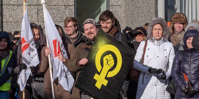 Menschen stehen beieinander. Sie haben Flaggen dabei