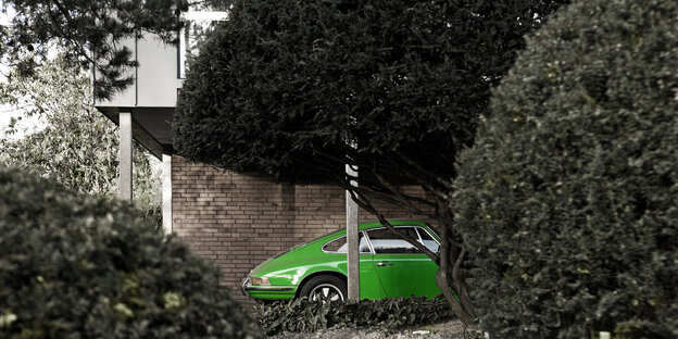 Grünes Auto neben einem stattlichen Wohnhaus geparkt, hinter Hecken