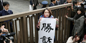 Japanische Journalistin Shiori Ito im Gerichtssaal, sie hält ein Banner hoch, auf dem auf japanisch "Sieg" steht