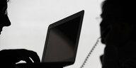 Schattenfoto: eine Person an einem Laptop, die von jemanden abgehört wird
