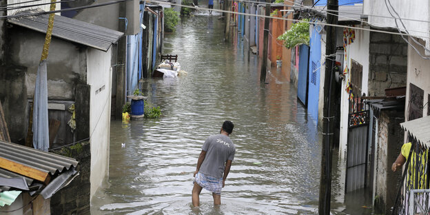Nach starken Regenfällen watet ein Mann durch eine überflutete Straße in seiner Nachbarschaft.
