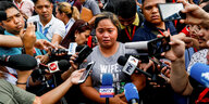 Die Tochter einer der getöteten Journalisten ist umringt von Mikrofonen und Reportern
