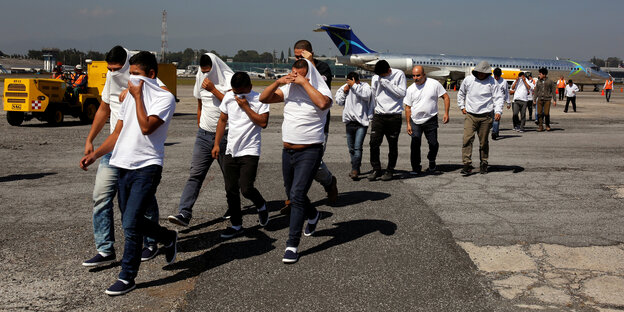 Deportierte Migranten verlassen ein Flugzeug
