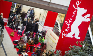 Menschen sitzen vor den Vorverkaufsschaltern der Berlinale