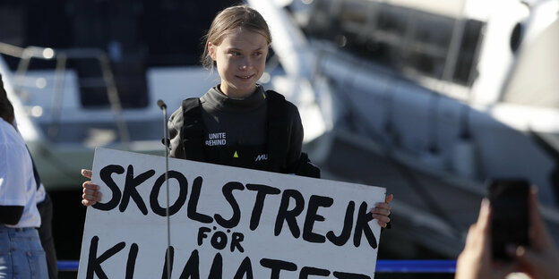 Mädchen steht mit Schild auf einem Schiff, es ist Greta Thunberg, auf dem Schild steht auf schwedisch "Schulstreik für das Klima"