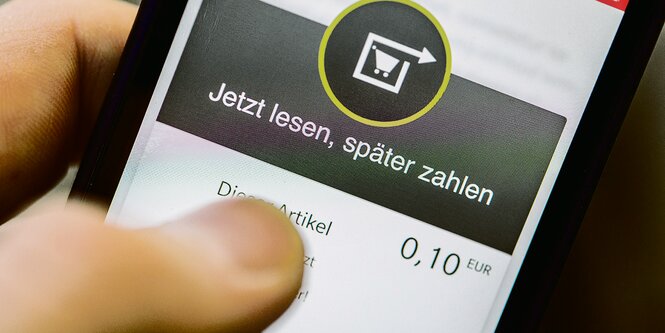 Daumen auf der Bezahl-App eines Smartphones