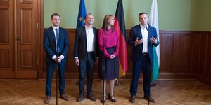 Michael Kretschmer, Katja Meier, Wolfram Günther und Martin Dulig stehen vor Mikrofonen. Im Hintergrund EU-, Deutschland-, und Sachsenflagge.