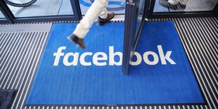 Das Facebook-Logo spiegelt sich in einem auf einer Tastatur liegenden Smartphone