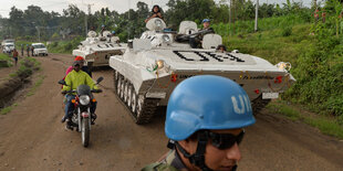 Im Vordergrund ein Blauhelm-Soldat, im Hintergrund Panzer.