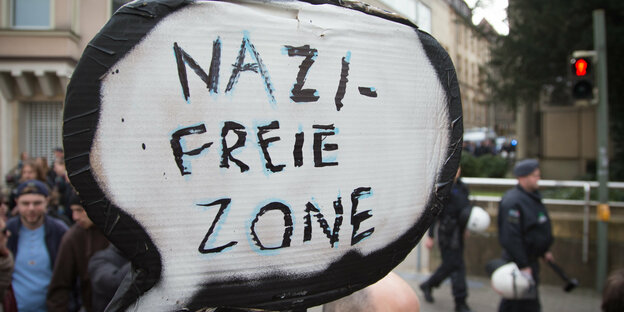 Auf einem Protestschild steht "Nazifreie Zone"
